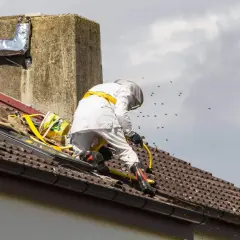 Specjalista w kombinezonie na dachu walczy z rojem os, szukając sposobu, jak odstraszyć osy z poddasza.