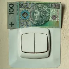 Sto złotych na włączniku światła symbolizuje wysokie rachunki za prąd, np. w taryfie G11 PGE.