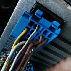 Niebieska wtyczka z przewodami, w tym żółtym i białym, podłączona do radia samochodowego. Prawdopodobnie część instalacji CAN bus.