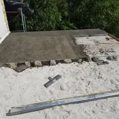 Budowa dachu z wykorzystaniem styrobetonu. Widać świeżo wylany materiał, który czeka na dalsze prace. Kluczowe są odpowiednie proporcje styrobetonu.