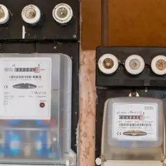 Dwa liczniki energii elektrycznej, jeden z czerwonym wskaźnikiem "AWARIA". Uważaj na oszustów przy tauron wymiana licznika.
