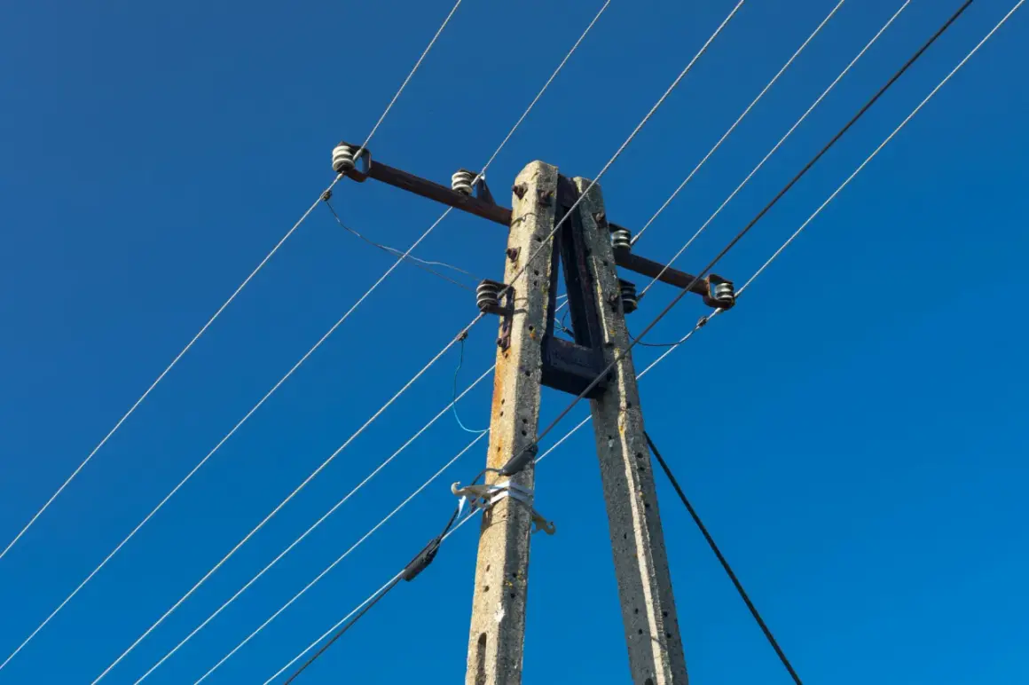 Betonowy słup energetyczny z przewodami na tle błękitnego nieba.