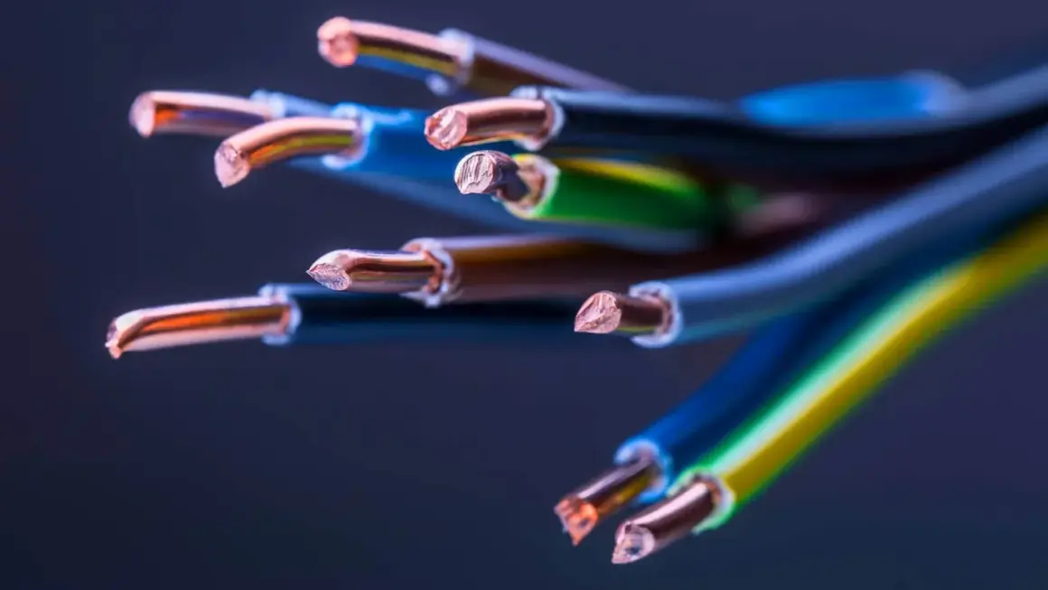 Zbliżenie na końcówki przewodów miedzianych, ukazujące różne rodzaje kabli elektrycznych w izolacjach niebieskiej, zielono-żółtej i brązowej.