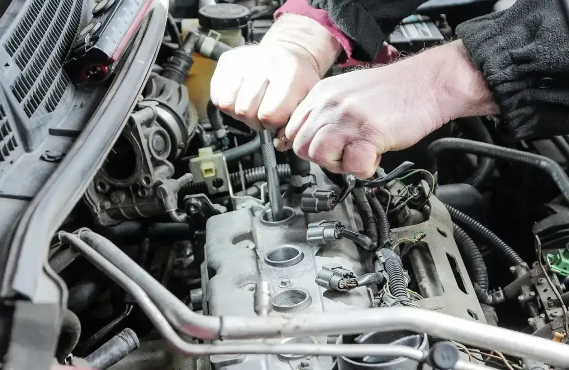 Mechanik wymienia świece zapłonowe w silniku. Pamiętaj o regularnej wymianie, by silnik pracował sprawnie.