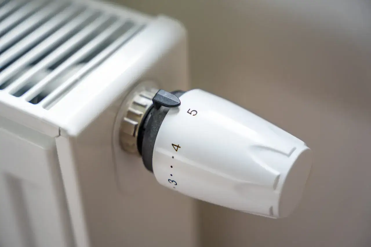 Biały grzejnik z termostatem ustawionym na 5. Pokrętło do regulacji temperatury pozwala na precyzyjne kryzowanie grzejnika.