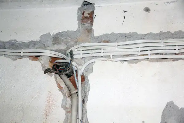 Widoczne przewody i puszka instalacyjna świadczą o starej instalacji elektrycznej, która wymaga modernizacji.