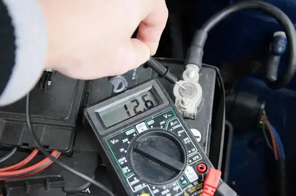 Pomiar napięcia akumulatora multimetrem, wskazanie 12.6V. Może to być etap diagnostyki przed odsiarczanie akumulatora.