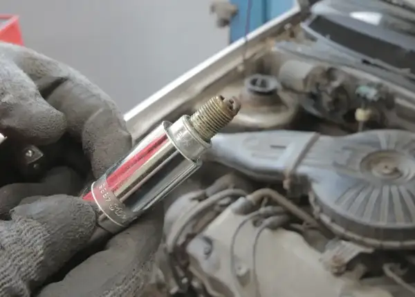 Ręka w rękawicy trzyma świecę zapłonową, potencjalną przyczynę błędu dtc p0301 renault.