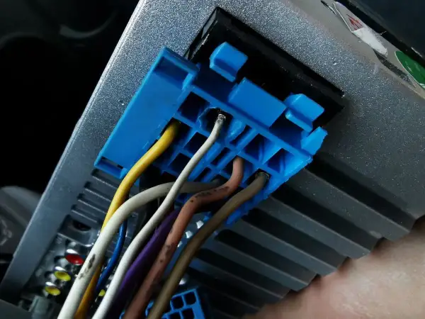 Niebieska wtyczka z przewodami, w tym żółtym i białym, podłączona do radia samochodowego. Prawdopodobnie część instalacji CAN bus.