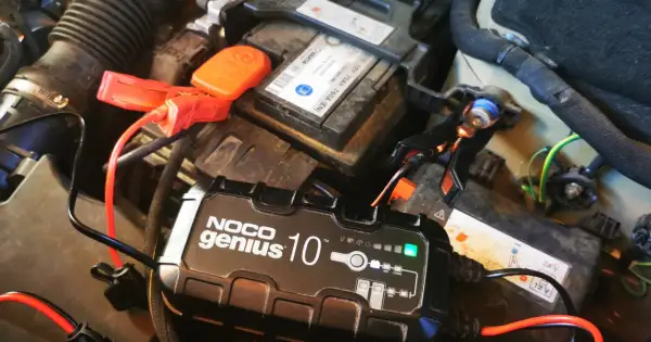 Ładowanie akumulatora na mrozie. Urządzenie NOCO Genius 10 podłączone do akumulatora samochodowego, by zapewnić mu energię w zimne dni.