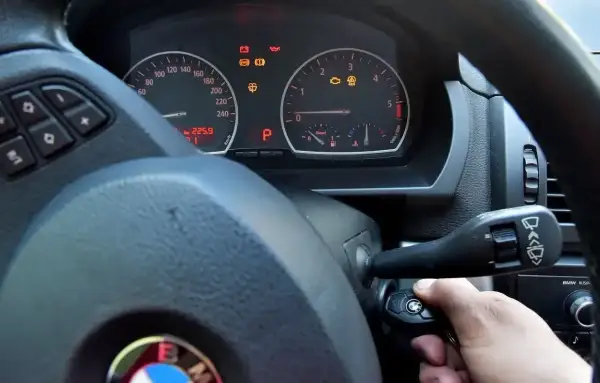 Ręka przekręca kluczyk w stacyjce BMW. Kontrolki na desce rozdzielczej świecą, ale rozrusznik nie kręci tylko cyka.
