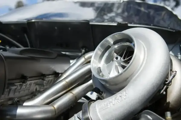 Błyszcząca turbosprężarka w silniku p0299 vw. Metalowe kolektory wydechowe i błyszcząca obudowa silnika.